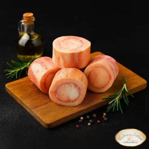 Kości Wołowe Szpikowe cięte na desce i ciemnym tle dekorowane rozmarynem i oliwą