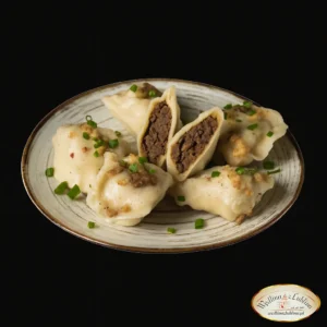 Pierogi z soczewicą na rustykalnym talerzu, przekrojone z widocznym wilgotnym farszem, posypane cebulką i szczypiorkiem